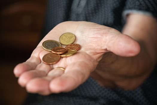 Couple of euro coins in elderly senior woman hand.