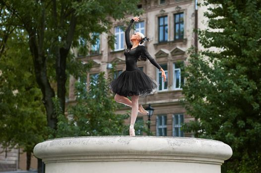 Gorgeous young graceful ballerina posing elegantly while performing outdoors in the town.