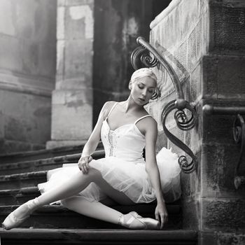 Resting grace. Monochrome soft focus portrait of a sensual young ballerina sitting on stairs