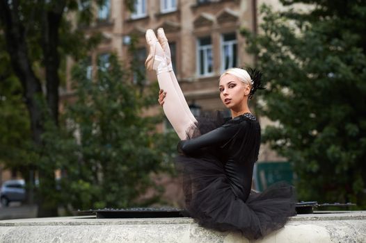 Shot of a gorgeous blonde haired young ballerina wearing black dress sitting outdoors posing gracefully looking to the camera copyspace balance beauty art performance dancer.