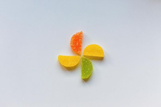 Four Sugar candies. Coloured green, yellow, orange. Shaped as half moon.