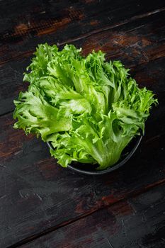 Raw organic green oak lettuce leaves, on old dark wooden table background