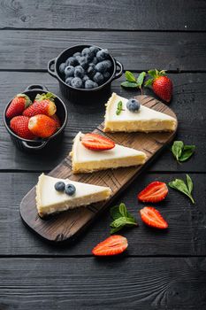 Portion of cheesecake with berrie, on black wooden table background