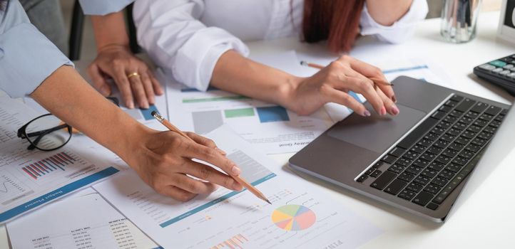 Close up business team using a calculator and laptop computer to calculate the numbers on his desk in a office.