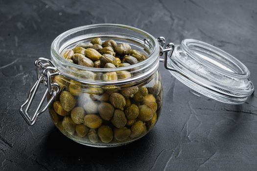 Baby capers in glas jar, on black background