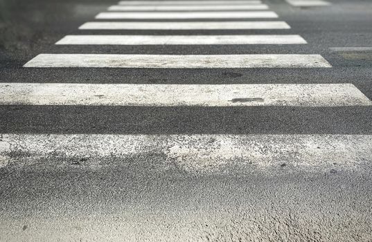 pedestrian crossing of a street with worn and ruined asphalt. Zebra crossing in a European city. Road signs and pedestrian crossing. Road safety