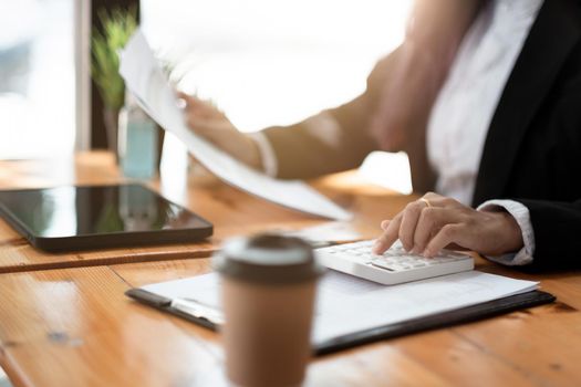 accountant working on desk using calculator for calculate finance report in cafe shop