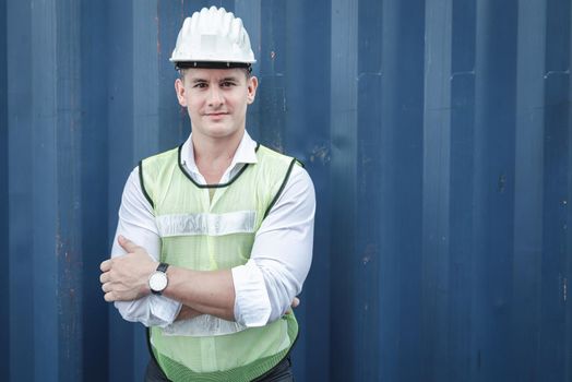 Portrait of Confident Transport Engineer Man in Safety Equipment Standing in Container Ship Yard. Transportation Engineering Management and Containers Logistics Industry, Shipping Worker Occupation