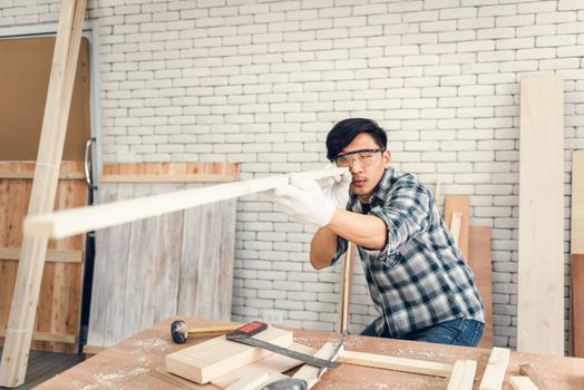 Carpenter Man is Working Timber Woodworking in Carpentry Workshops, Craftsman is Aiming Alignment to Timber Plank for Wooden Furniture in Workshop. DIY Workmanship, Job Carpenters Concept