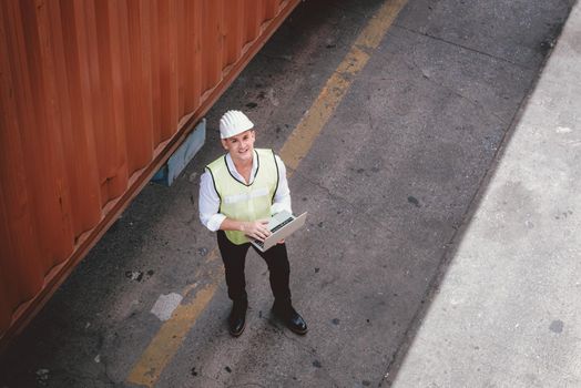 Container Shipping Logistics Engineering of Import/Export Transportation Industry, Transport Engineer is Controlling Management Containers Box on Laptop at Port Ship Loading Dock. Industrial Shipping