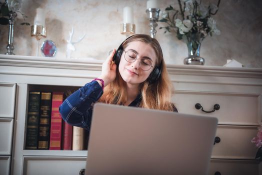 Leisure Activity and Home Relaxing Lifestyle Concept, Attractive Woman Having Enjoyment While Listening Music Songs Via Headphone on Laptop in Living Room. Relaxation Pursuit Entertainment at Home