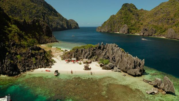 Tropical lagoon with sandy beach surrounded by cliffs, aerial view. El nido, Philippines, Palawan. Seascape with tropical rocky islands, ocean blue water. Summer and travel vacation concept