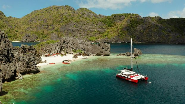 Tropical lagoon with sandy beach surrounded by cliffs, aerial view. El nido, Philippines, Palawan. Seascape with tropical rocky islands, ocean blue water. Summer and travel vacation concept