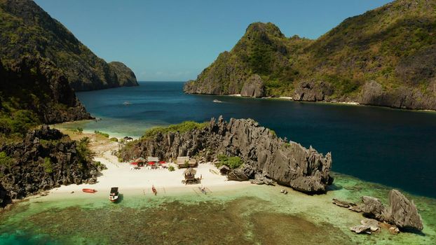 Tropical lagoon with sandy beach surrounded by cliffs, aerial view. El nido, Philippines, Palawan. Seascape with tropical rocky islands, ocean blue water. Summer and travel vacation concept