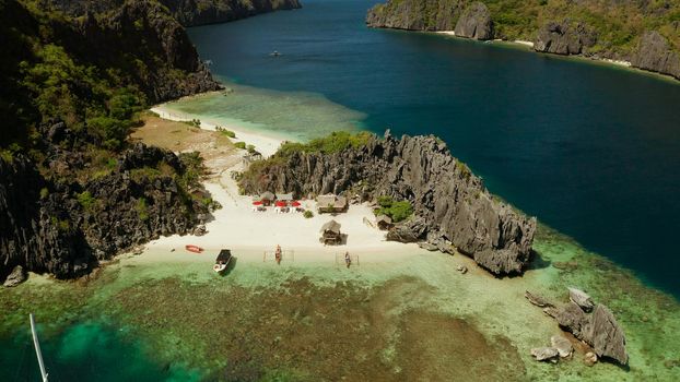 Tropical lagoon with sandy beach surrounded by cliffs, aerial view. El nido, Philippines, Palawan. Seascape with tropical rocky islands, ocean blue water. Summer and travel vacation concept