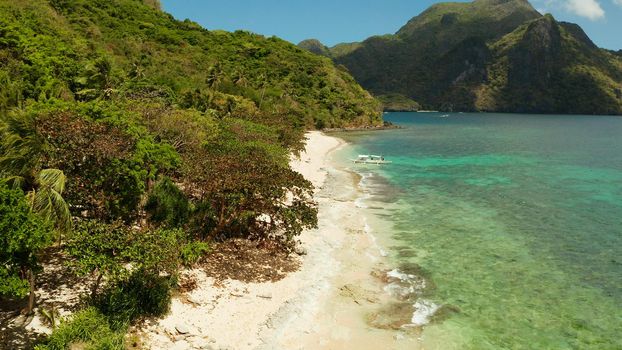 aerial view tropical beach on island with palm trees, blue lagoon and azure clear water. Helicopter Island in El Nido, Palawan Philippines. Tropical landscape with blue lagoon, coral reef