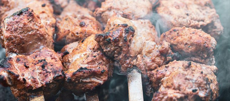Meat on skewers. Marinated shashlik preparing on a barbecue grill over charcoal. Appetizing meat grilled on skewers. Cooking shashlik. Grilling pork on coal