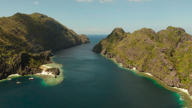 Tropical landscape bay with beach and clear blue water surrounded by cliffs, aerial drone. El nido, Philippines, Palawan. Seascape with tropical rocky islands, ocean blue water. Summer and travel vacation concept