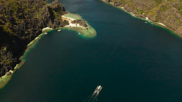 Tropical landscape bay with beach and clear blue water surrounded by cliffs, aerial drone. El nido, Philippines, Palawan. Seascape with tropical rocky islands, ocean blue water. Summer and travel vacation concept