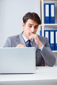 Young handsome businessman employee working in office at desk