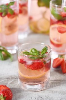 Summer strawberry cocktail or lemonade with basil. Cold refreshing organic soft drink with ripe berries in a glass