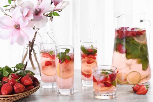 Summer strawberry cocktail or lemonade with basil. Cold refreshing organic soft drink with ripe berries in a glass