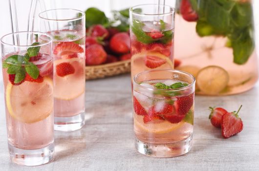 Summer strawberry cocktail or lemonade with basil. Cold refreshing organic soft drink with ripe berries in a glass