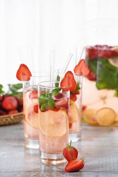 Summer strawberry cocktail or lemonade with basil. Cold refreshing organic soft drink with ripe berries in a glass