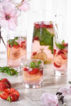 Summer strawberry cocktail or lemonade with basil. Cold refreshing organic soft drink with ripe berries in a glass