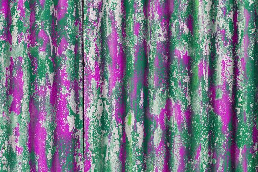 colorful motley peeled off green and pink paint layers on corrugated zinc coated steel sheet - full frame background and texture