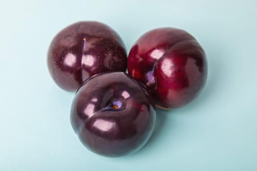 Three large plums on a blue background. Delicious berry for dessert.