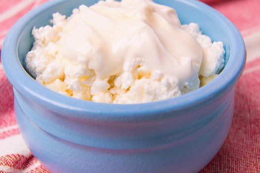Cottage cheese in a blue bowl with sour cream and honey. Morning breakfast.