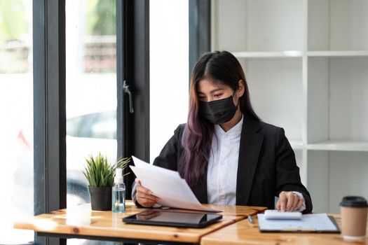Business woman wear mask while using calculator with computer laptop, Business accounting, budget and loan paper in office.