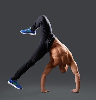 Never resting. Muscular young man doing a handstand shirtless showing off his strong body