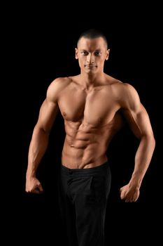 Gym king. Vertical portrait of a young attractive bodybuilder posing shirtless smiling to the camera