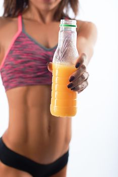 Vertical cropped shot of a sportswoman with muscular toned body holding out bottle of juice to the camera.