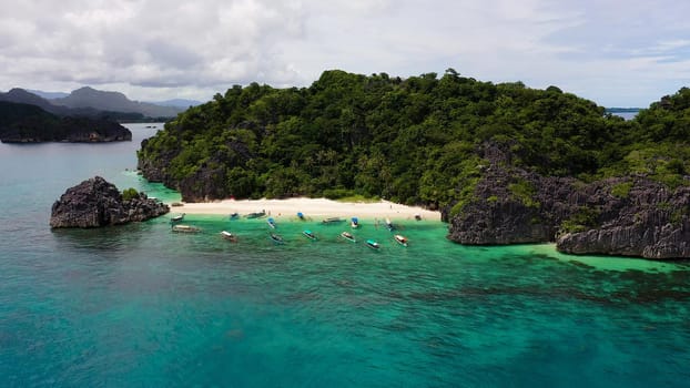 Tropical island with sandy with tourists and blue sea, aerial view. Lahos Island, Caramoan Islands, Philippines. Summer and travel vacation concept.