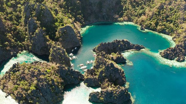 Tourist boats around the beautiful big and small lagoons, aerial view. lagoon, mountains covered with forests.coves with blue water among the rocks. Seascape, tropical landscape. Palawan, Philippines