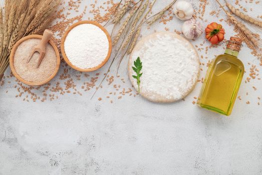 The ingredients for homemade pizza dough with wheat ears ,wheat flour and wheat grains set up on white concrete background.