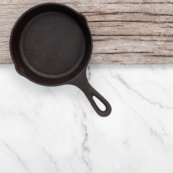 Empty old cast iron skillet set up on white marble  background with flat lay and copy space.