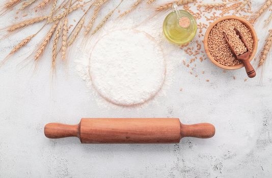 The ingredients for homemade pizza dough with wheat ears ,wheat flour and wheat grains set up on white concrete background.