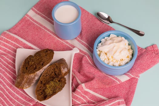 Cottage cheese in a blue bowl with sour cream and honey. Toasted bread in a plate. Morning breakfast.