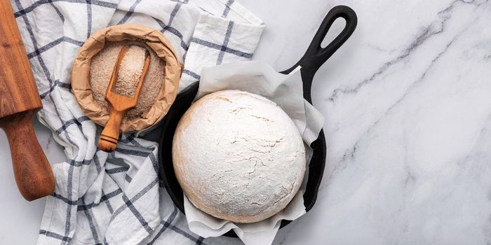 Fresh raw homemade yeast dough resting in cast iron skillet on marble table flat lay.