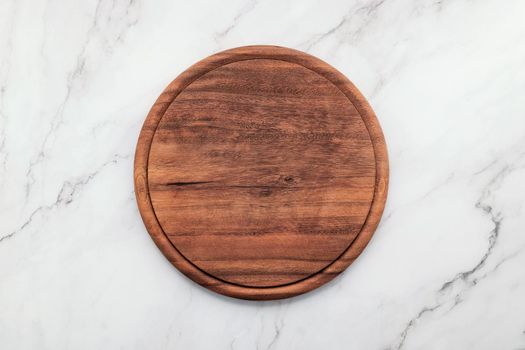 Empty wooden pizza platter set up on marble stone kitchen table. Pizza board on white marble background flat lay and copy space.