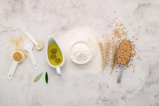 The ingredients for homemade pizza dough with wheat ears ,wheat flour and olive oil set up on white concrete background. top view and copy space.