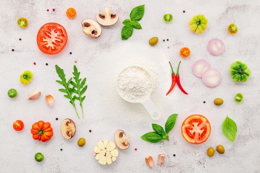 The ingredients for homemade pizza set up on white concrete background.