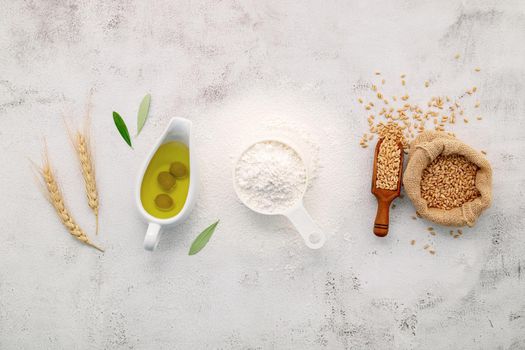 The ingredients for homemade pizza dough with wheat ears ,wheat flour and olive oil set up on white concrete background. top view and copy space.