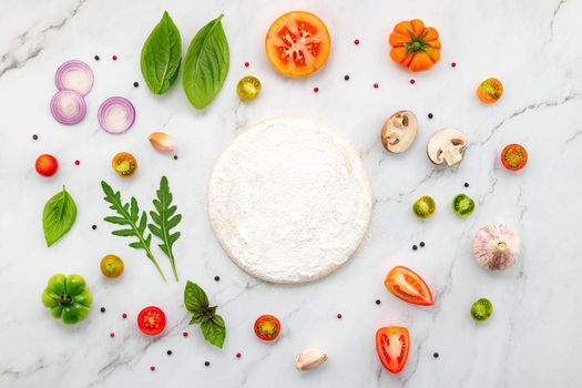 The ingredients for homemade pizza set up on white marble background with copy space and top view.