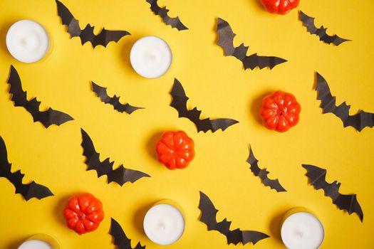 Halloween background, orange decorative plastic pumpkin black paper bat round candle yellow cardboard Thanksgiving greeting card pattern