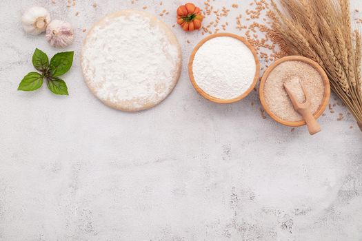 The ingredients for homemade pizza dough with wheat ears ,wheat flour and wheat grains set up on white concrete background.